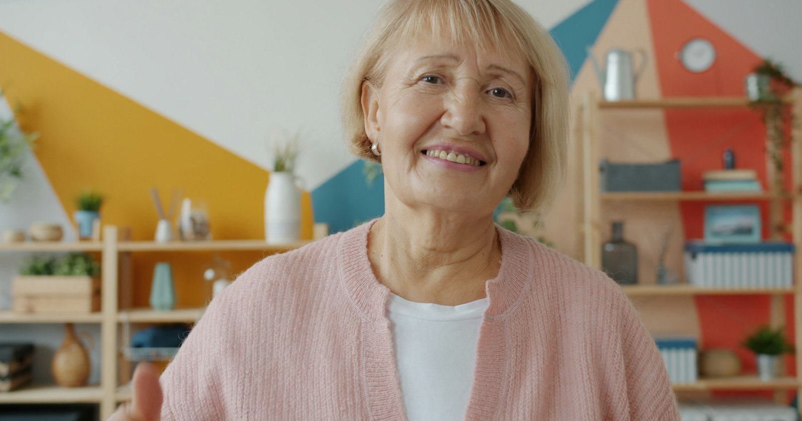 Madre mayor sonriente con una chaqueta rosa en casa