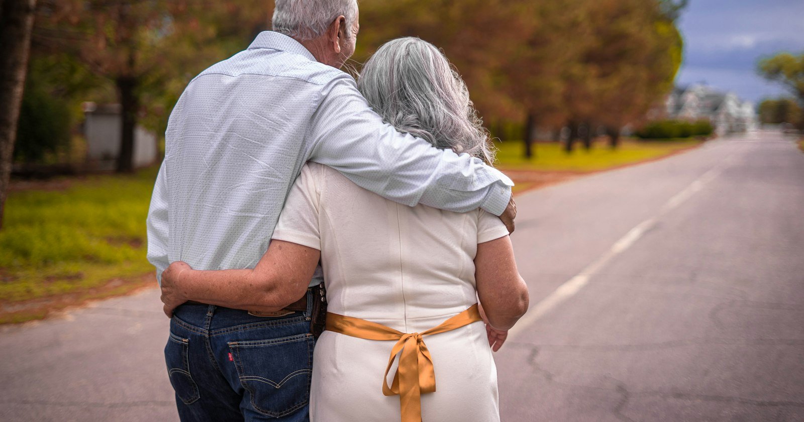 Abuelos de pelo cano paseando del brazo por un camino
