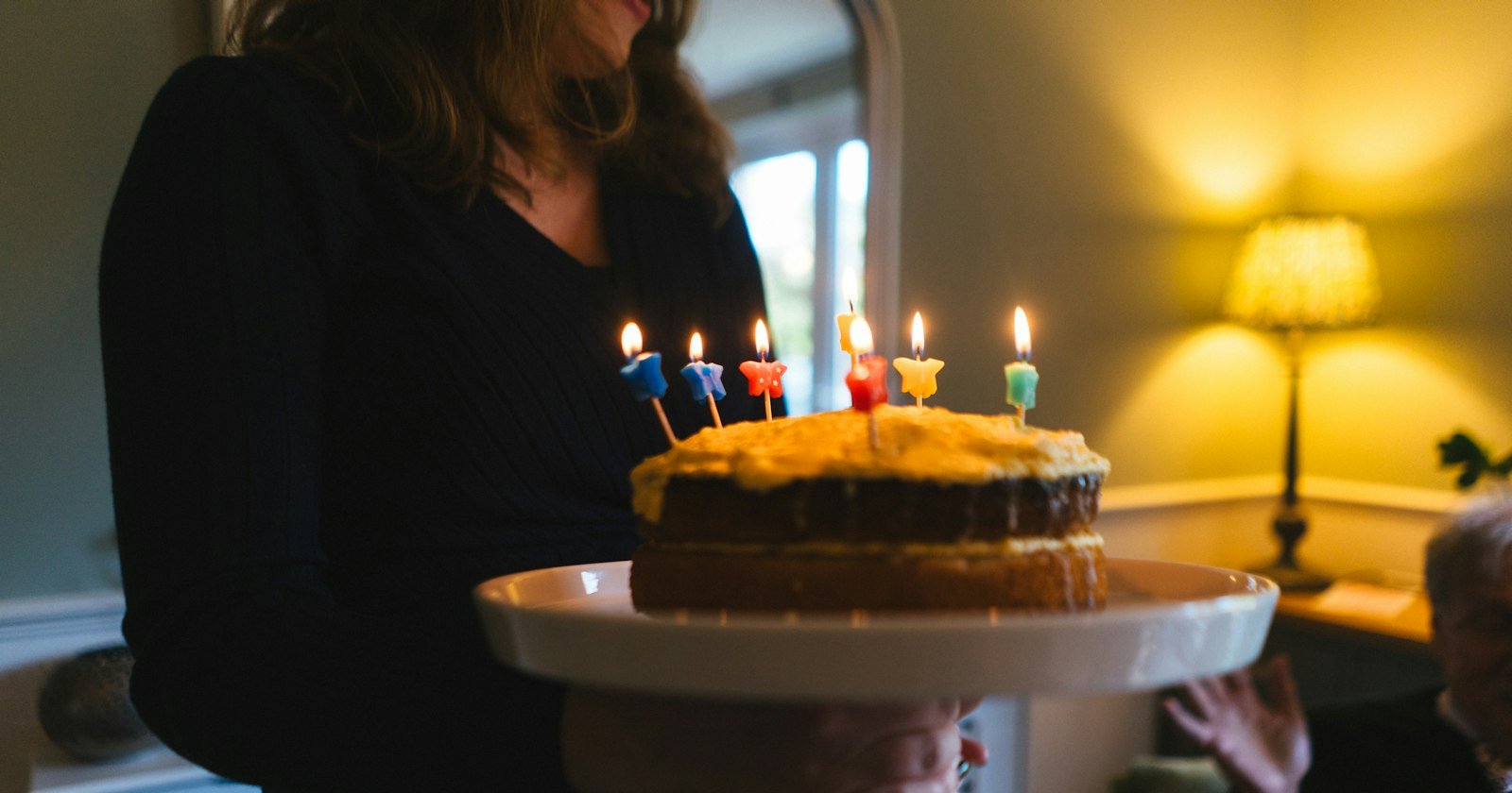 Mujer sosteniendo una tarta de cumpleaños con las velas encendidas