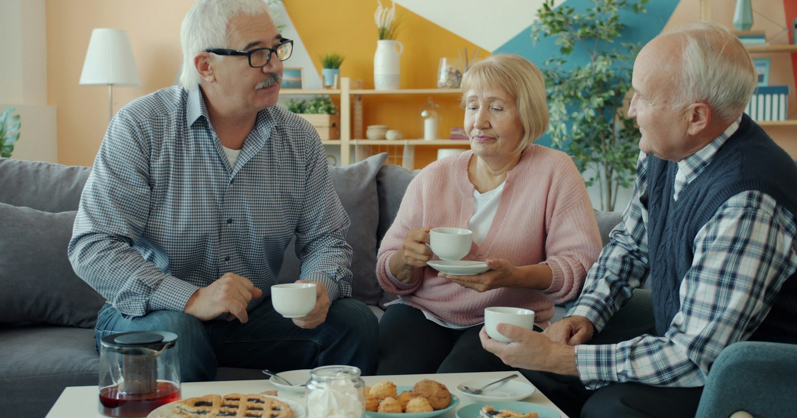 Tres personas jubiladas tomando café y conversando en casa